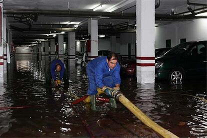Dos trabajadores intentaban ayer achicar agua de un sótano inundado en Córdoba.