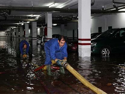 Dos trabajadores intentaban ayer achicar agua de un sótano inundado en Córdoba.