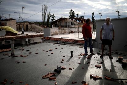 Dos hombres obervan los daños que se han producido por las tormentas en la terraza de una casa de la localidad griega de Nea Plagia.