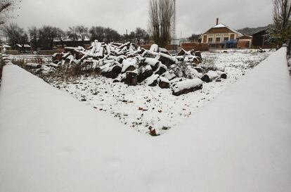 Bajo una de las primeras nevadas de la temporada se ven junto a las naves unos 1.500 metros cúbicos de madera.