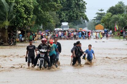 Residentes del municipio de Mabini cruzan caminos inundados por el tif&oacute;n Bopha.  