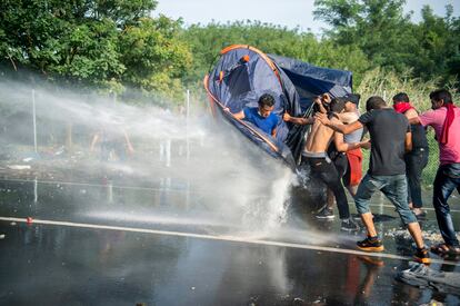 La policía húngara lanza un cañón de agua para disuadir a un grupo de refugiados que se protegen con una tienda de campaña en el paso fronterizo de Horgos (Serbia).