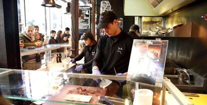 Dos camareros trabajan en un puesto del Mercado de San Miguel, en Madrid