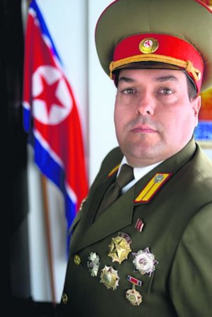 Alejandro Cao de Benós, fotografiado en Salomó (Tarragona), donde vive, con su uniforme y junto a la bandera de Corea del Norte.