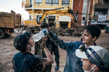 Voluntarios se ayudan, unos a otros, para poder beber agua potable en Paiporta, este lunes. 