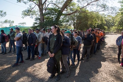 Trabajadores paraguayos esperan a ser autorizados para salir en la entrada principal de Paraíso Verde al final de su jornada.