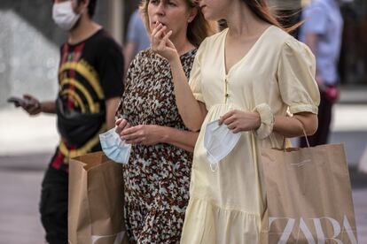 Dos mujeres sujetan sus mascarillas en una calle de Madrid, este sábado.