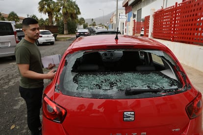 Un joven junto  su coche que presenta la luna trasera rota debido a la granizada registrada en la noche de este lunes, en El Ejido (Almería).
