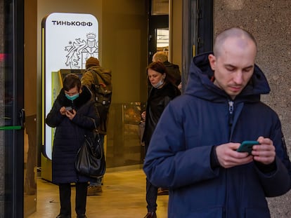 A man and a woman use their cell phones in Moscow in March 2022.