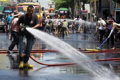 Un empleado de la limpieza limpia una calle de Bangkok, escenario de los enfrentamientos de la semana pasada
