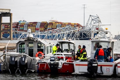 Personal de rescate se reúne en la orilla del río Patapsco tras el accidente del carguero (al fondo), este martes en Baltimore. 