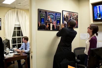 19 de abril 2013. Obama arruma os quadros com fotografias, pendurados na parede do gabinete de imprensa da Casa Branca.