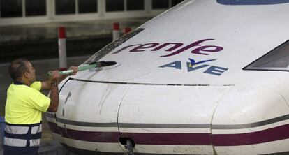 Un operario limpia la locomotara de un tren de alta velocidad de Renfe.