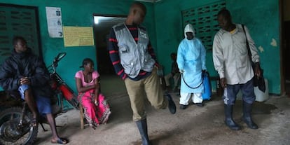 Personal sanitario de Liberia desinfecta el calzado de personas que salen de un centro de aislamiento por &eacute;bola.