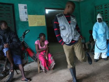 Personal sanitario de Liberia desinfecta el calzado de personas que salen de un centro de aislamiento por &eacute;bola.