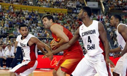 Felipe Reyes intenta anotar ante dos jugadores de Canadá.