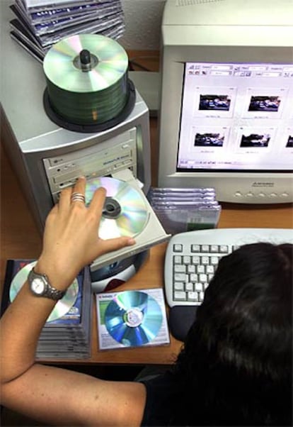 Una mujer introduce un disco compacto en un ordenador.