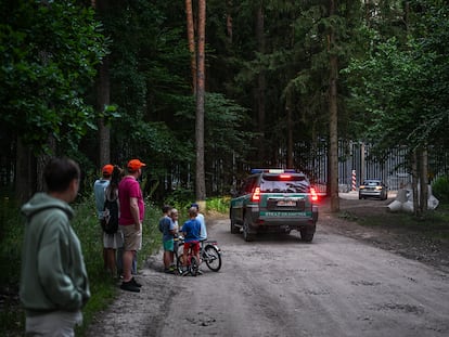 A group of people observe the fence on the border between Poland and Belarus, in the town of  Białowieża, in July of 2023