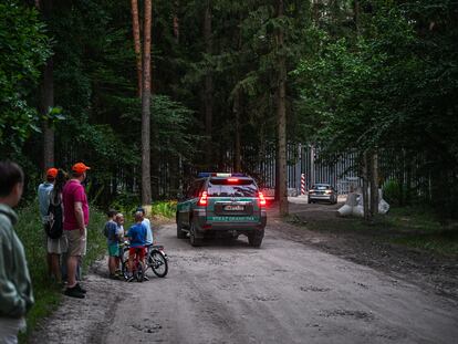 Un grupo de personas observa en la distancia la valla en la frontera entre Polonia y Bielorrusia, en Bialowieza, el pasado julio.