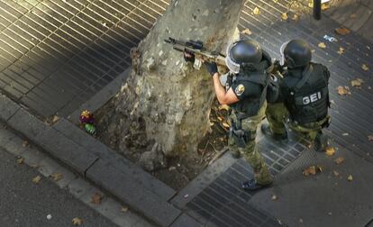 Policías parapetados tras uno de los árboles de la Rambla esperando el desalojo del restaurante la Luna de Estambul.