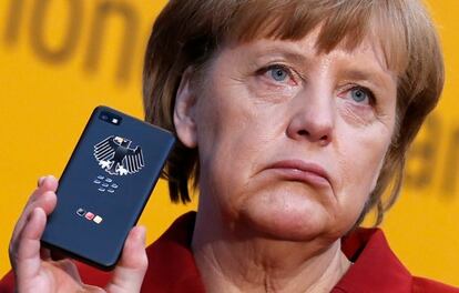 German Chancellor Merkel holds a BlackBerry Z10 smartphone featuring high security Secusite software at the booth of Secusmart during her opening tour at the CeBit computer fair in Hanover