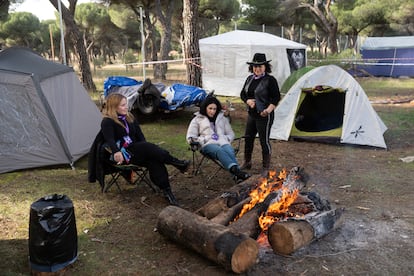 Tres mujeres se calientan junto al fuego en la concentración motera Pingüinos, este viernes.