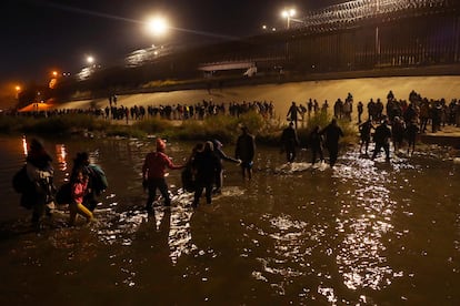 Un grupo de migrantes se toma de las manos para poder cruzar el río Bravo, que separa a Ciudad Juárez y El Paso.