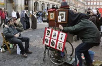 Una pareja de turistas nostálgicos se hace una foto con una vieja cámara, en la Plaza Mayor de Madrid. EFE/Archivo