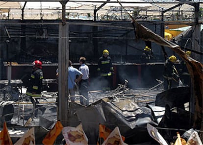 Bomberos trabajan en la caseta incendiada en la Feria de Málaga.