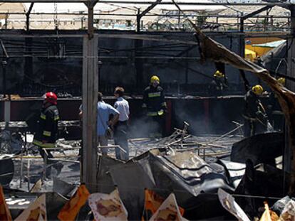 Bomberos trabajan en la caseta incendiada en la Feria de Málaga.