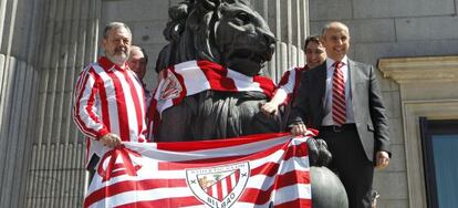 Diputados vascos colocan una bandera del Athletic en uno de los leones del Congreso de los Diputados.