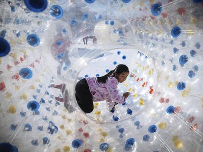 Una ni&ntilde;a juega en el interior de una gran bola de pl&aacute;stico durante el Festival de Primavera en Pek&iacute;n (China). 