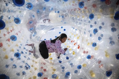 Una ni&ntilde;a juega en el interior de una gran bola de pl&aacute;stico durante el Festival de Primavera en Pek&iacute;n (China). 