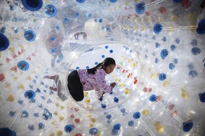 Una niña juega en el interior de una gran bola de plástico durante el Festival de Primavera en Pekín (China).