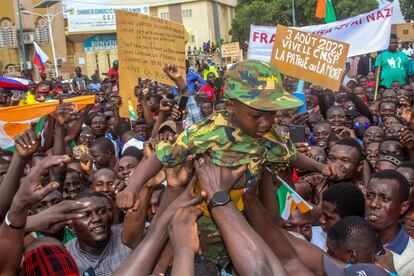 Men a hold a child dressed in military uniform as they gather with thousands of anti-sanctions protestors in support of the putschist soldiers in the capital Niamey, Niger August 3, 2023.