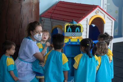 Una educadora muestra a los niños un robot que toma la temperatura en una escuela infantil, esta mañana en Madrid