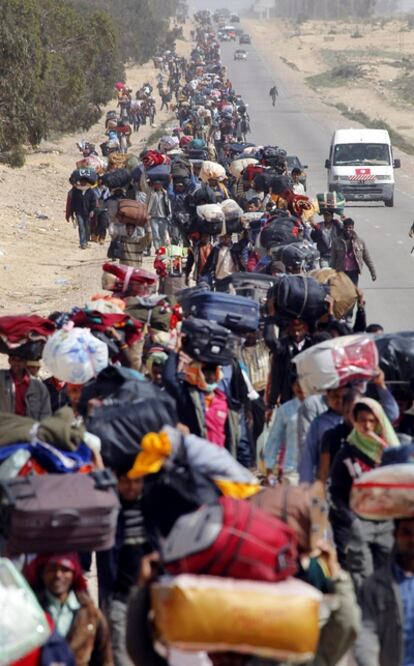 Larga fila de emigrantes que han salido de Libia por Ras el  Ajdir y se dirigen a un campamento instalado a 5 kilómetros de la frontera.