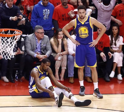 El delantero del Golden State Warriors, Kevin Durant (izquierda) se toca su tobillo tras lesionarse en una jugada contra los Raptors de Toronto.