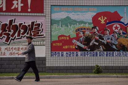 Un hombre pasa junto a un cartel de propaganda en una calle de Pyongyang.