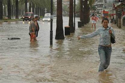 Varias personas cruzan por una calle de Salou que ayer por la tarde permaneca inundada.