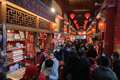 Varias personas se reúnen en una tienda en la calle comercial Qianmen el primer día del Año Nuevo Lunar chino, en Beijing (China). Es habitual decorar las calles y las casas para atraer la buena suerte. Una de las decoraciones más frecuente es el pez o 'yú' que atrae la abundancia y si es de color rojo ahuyenta a Nian, una bestia que habita bajo el mar y que sale de su escondite al inicio de la primavera para atacar a la gente.