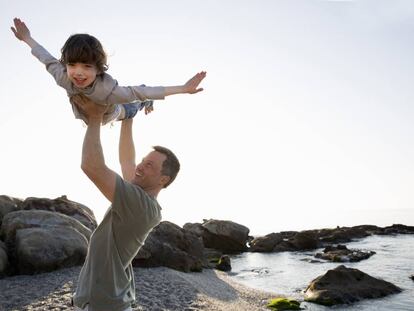 Un padre juega con su hijo en la playa. 