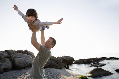 Un padre juega con su hijo en la playa. 