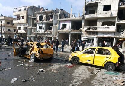 Ciudadanos sirians en el lloc on van explotar dos cotxes bomba aquest diumenge en Homs.