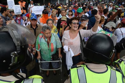 La coalición Mesa de la Unidad Democrática (MUD) ha convocado a los jubilados a marchar hacia la sede de la Defensoría del Pueblo. En la foto, un grupo de manifestantes gritan consignas a la policía antidisturbios en Caracas.