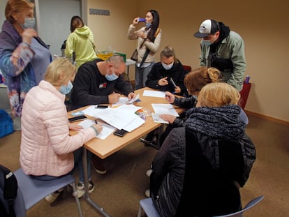 Ciudadanos de Ucrania rellenan formularios mientras esperan su turno en la Oficina de Documentación que la Policía Nacional ha instalado en Alicante.