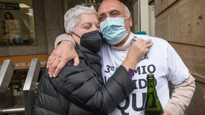 Isabel, una agraciada con un décimo del tercer premio de la lotería, se abraza al lotero que ha repartido la suerte en Valencia, MIguel Ángel Olmedo.