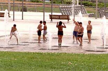 Un grupo de niños, ayer, se refresca en las fuentes del Campo de las Naciones.