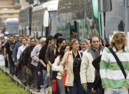 Los ciudadanos hacen cola para tomar un autobús en la plaza de Espanya.