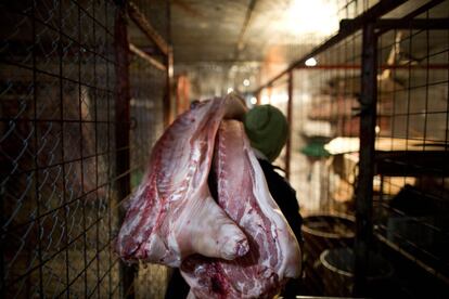 Un vendedor saaca de la cámara frigorifica los costillares de cerdo que acaba de comprar una señora para su negocio de comidas.